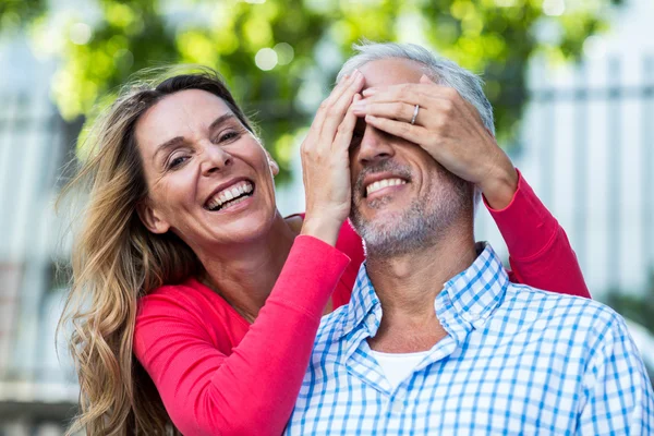 Woman covering eyes of man