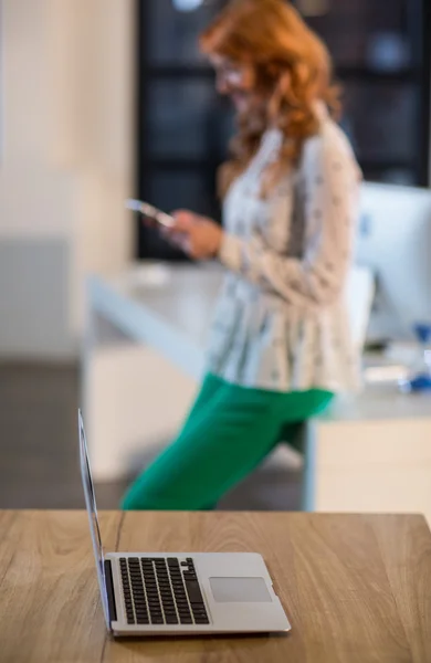 Laptop on table with woman standing