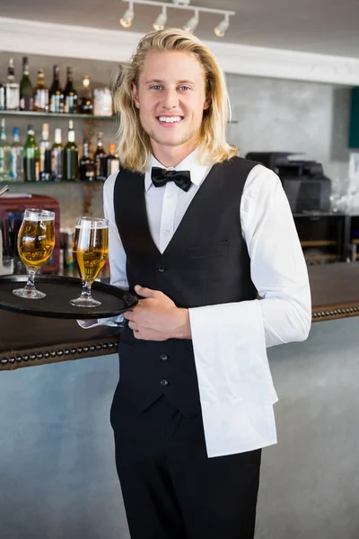 Portrait of waiter holding tray with glasses of beer