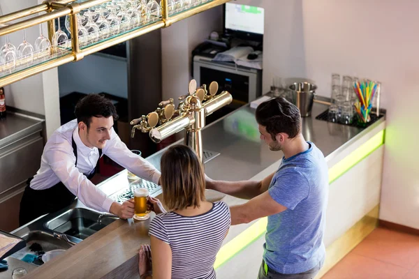 Barkeeper serving beer to couple