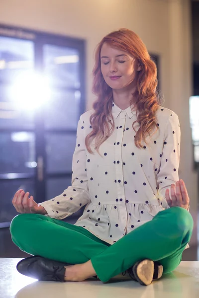 Young businesswoman doing yoga in office