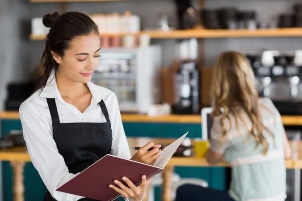 Smiling waitress writing in a file