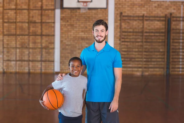 Portrait of sports teacher standing with his student in basketball court