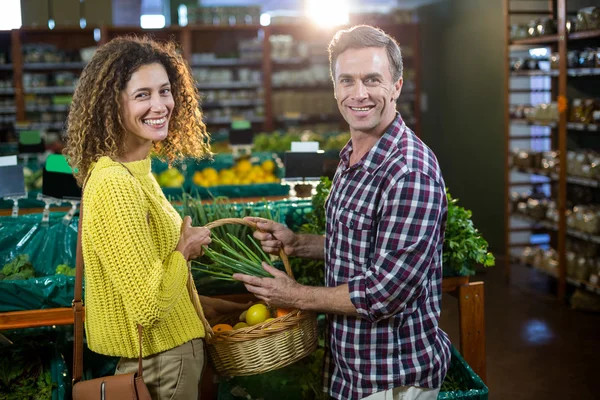Happy couple buying vegetables in organic section