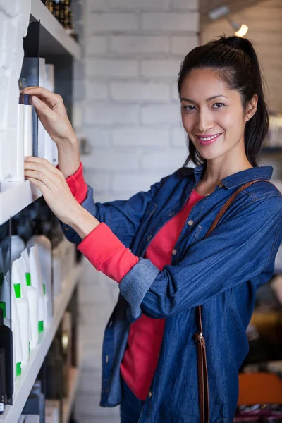 Smiling female hair dresser selecting shampoo