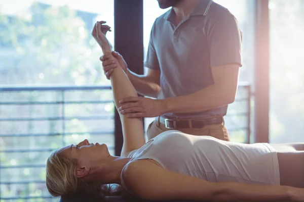 Woman receiving hand therapy exercises from physiotherapist