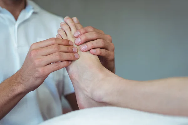 Physiotherapist giving foot massage to a woman