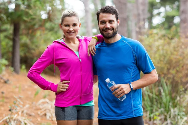 Athletic couple standing together in forest