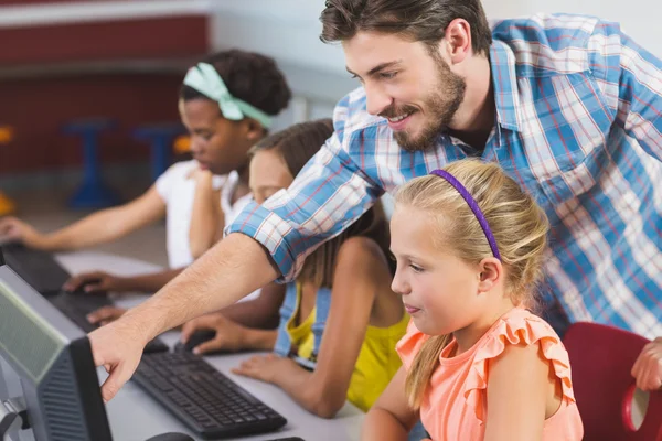 Teacher assisting schoolgirls in learning computer
