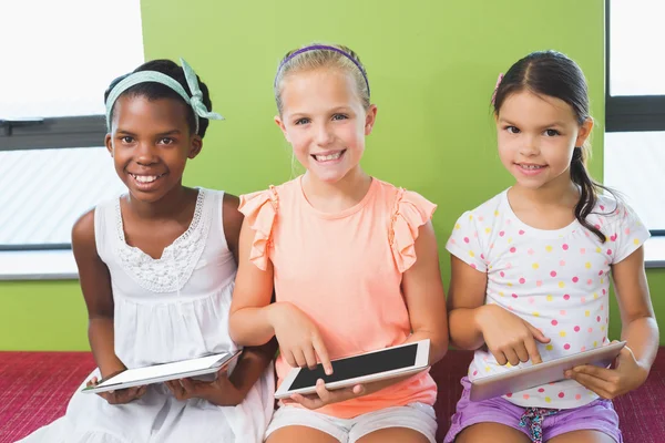 Schoolgirls using digital tablet in library