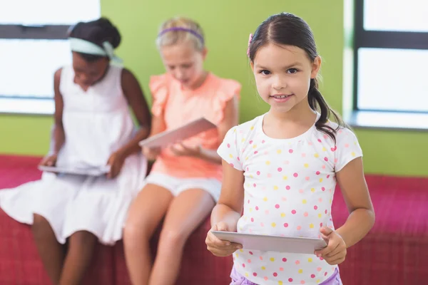 Schoolgirl holding digital tablet in library