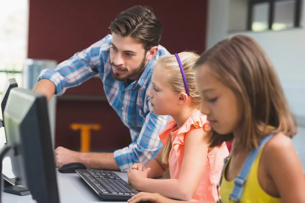 Teacher assisting schoolgirls in learning computer