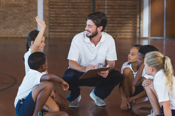 Sports teacher having discussion with his students