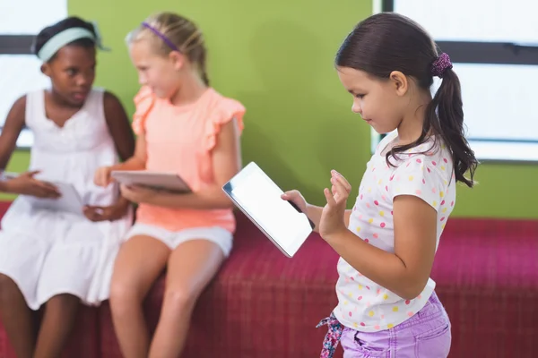 Schoolgirl using digital tablet in library