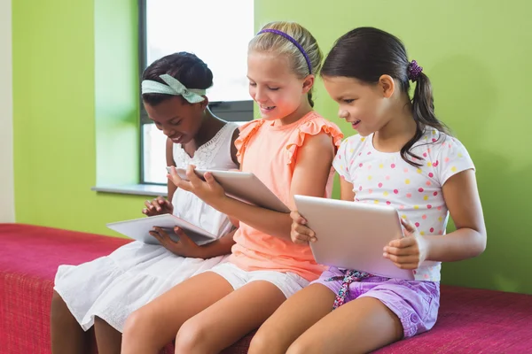 Schoolgirls using digital tablet in library