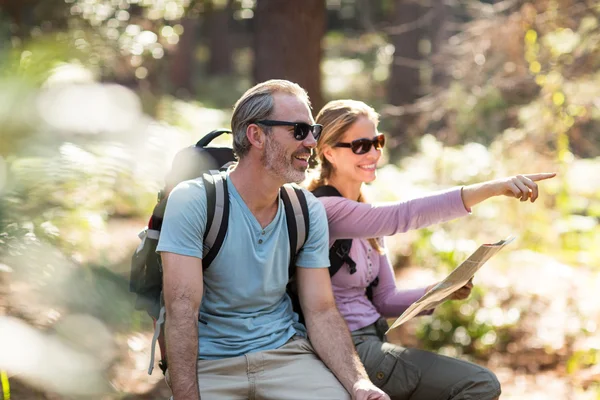 Hiker couple with map pointing in the distance