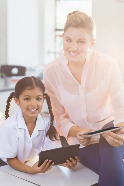 Teacher and schoolgirl using digital tablet in classroom
