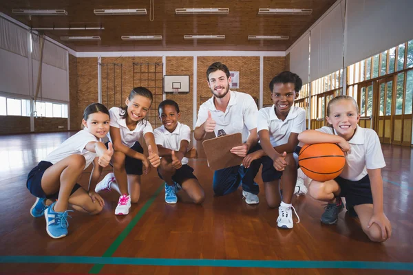 Portrait of sports teacher and school kids in basketball court