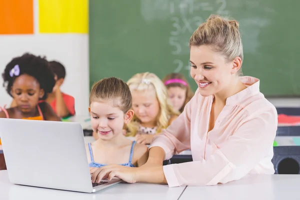 Teacher teaching schoolgirl on laptop