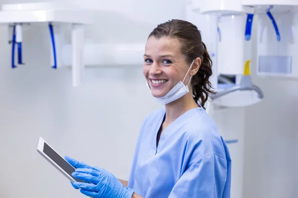 Smiling dental assistant using digital tablet