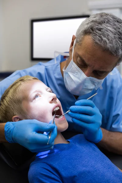 Dentist examining a young patient with tools