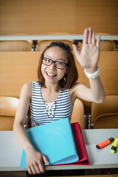 Young woman raising hand in classroom