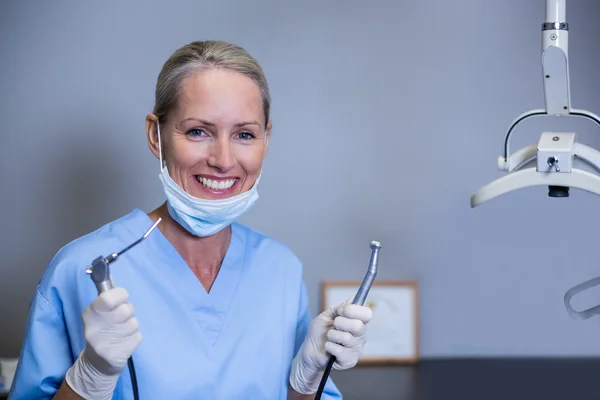 Smiling dental assistant holding dental tools in clinic