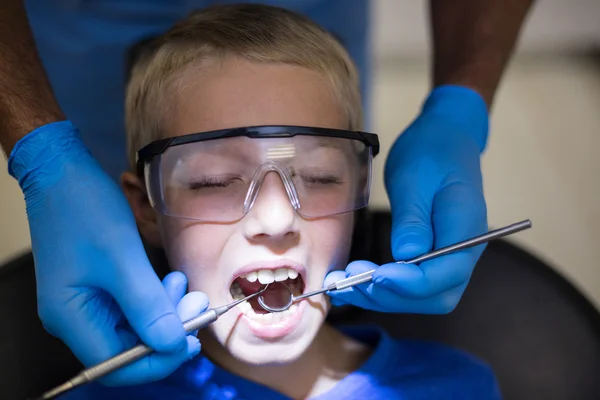 Dentist examining a young patient with tools