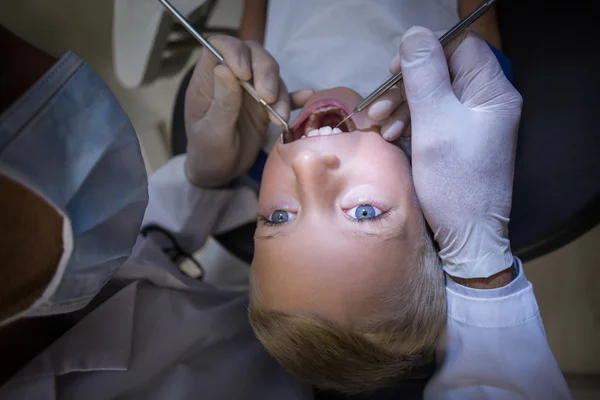 Dentist examining a young patient with tools