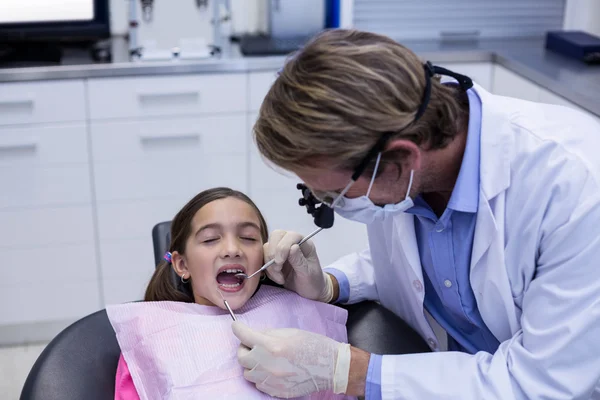 Dentist examining a young patient with tools