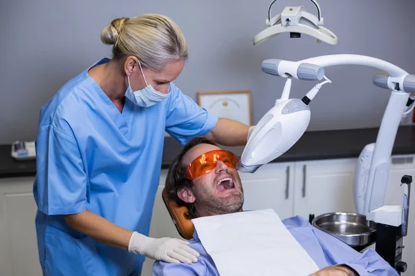 Dental assistant examining young patient mouth