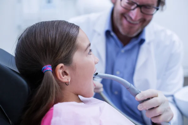 Dentist examining a young patient with tools