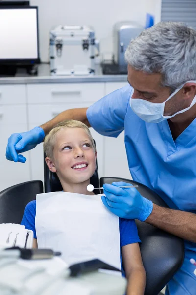 Dentist interacting with young patient while examining