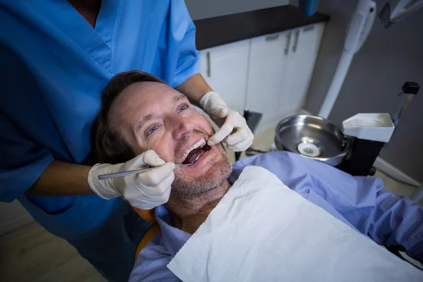 Dentist examining a young patient with tools