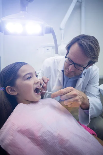 Dentist examining a young patient with tools