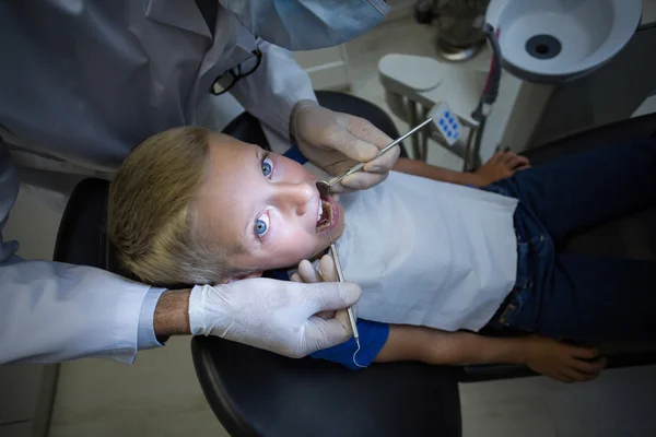 Dentist examining a young patient with tools