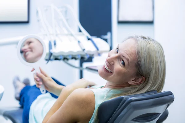 Female patient smiling while holding mirror