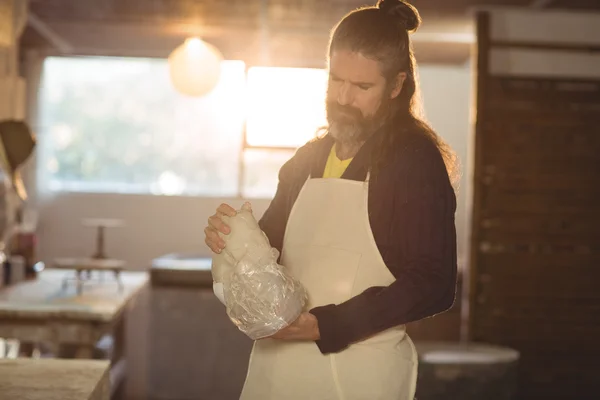 Male potter removing plastic cover