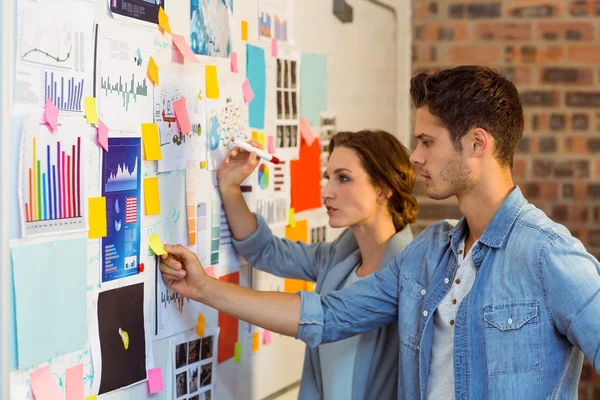 Business executives putting sticky notes on whiteboard