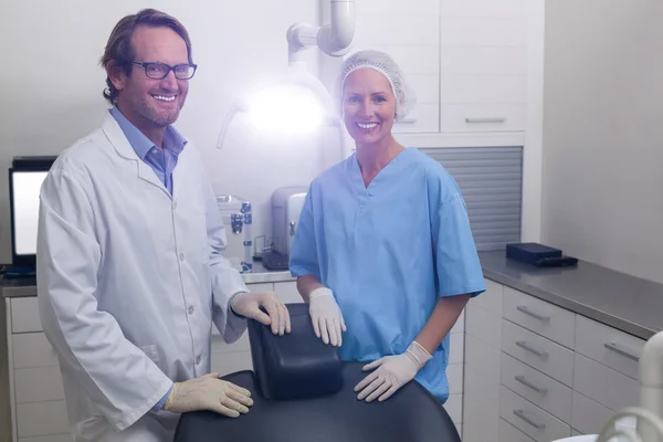 Smiling dentist and dental assistant standing together in dental