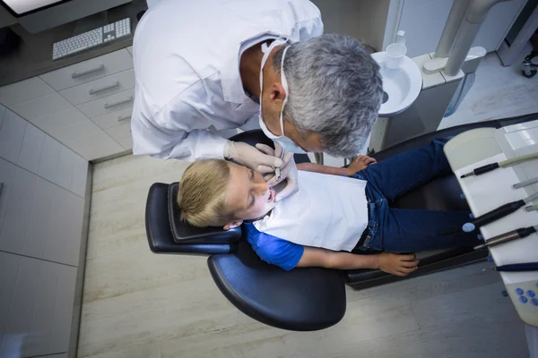 Dentist examining a young patient with tools