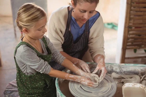 Female potter assisting girl