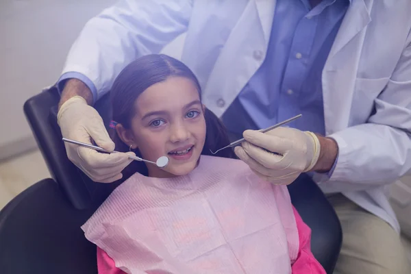 Dentist examining a young patient with tools