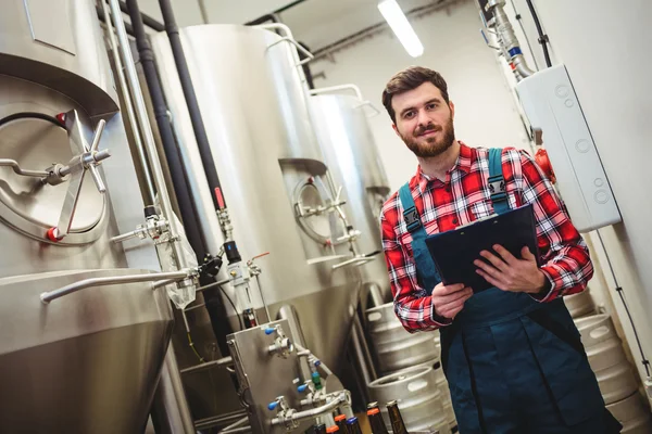 Portrait of manufacturer holding writing pad in brewery