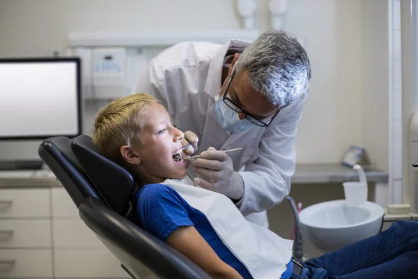 Dentist examining a young patient with tools