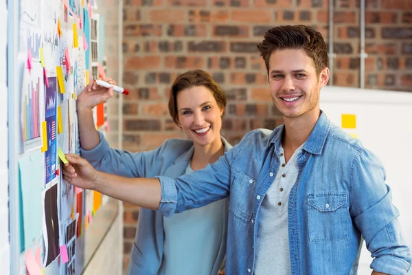 Business executives putting sticky notes on whiteboard