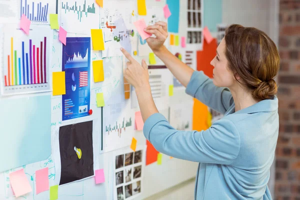 Businesswoman putting sticky notes on whiteboard