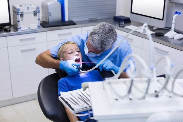 Dentist examining a young patient with tools