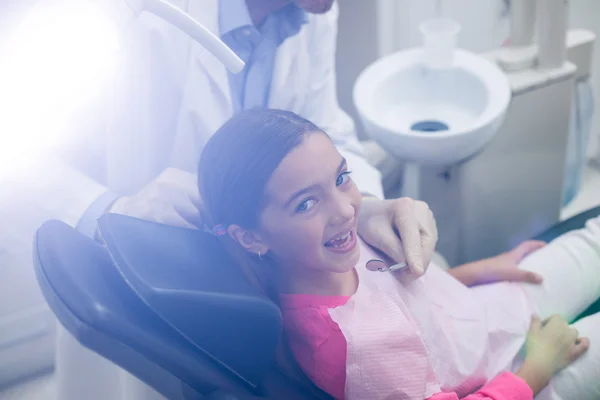 Dentist examining a young patient with tools