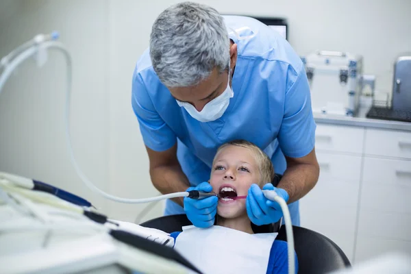 Dentist examining a young patient with tools